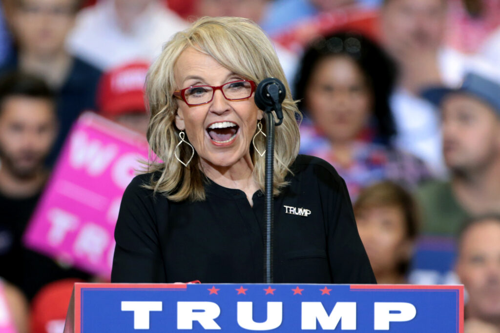 Former Arizona Governor Jan Brewer at a podium at a Trump Rally